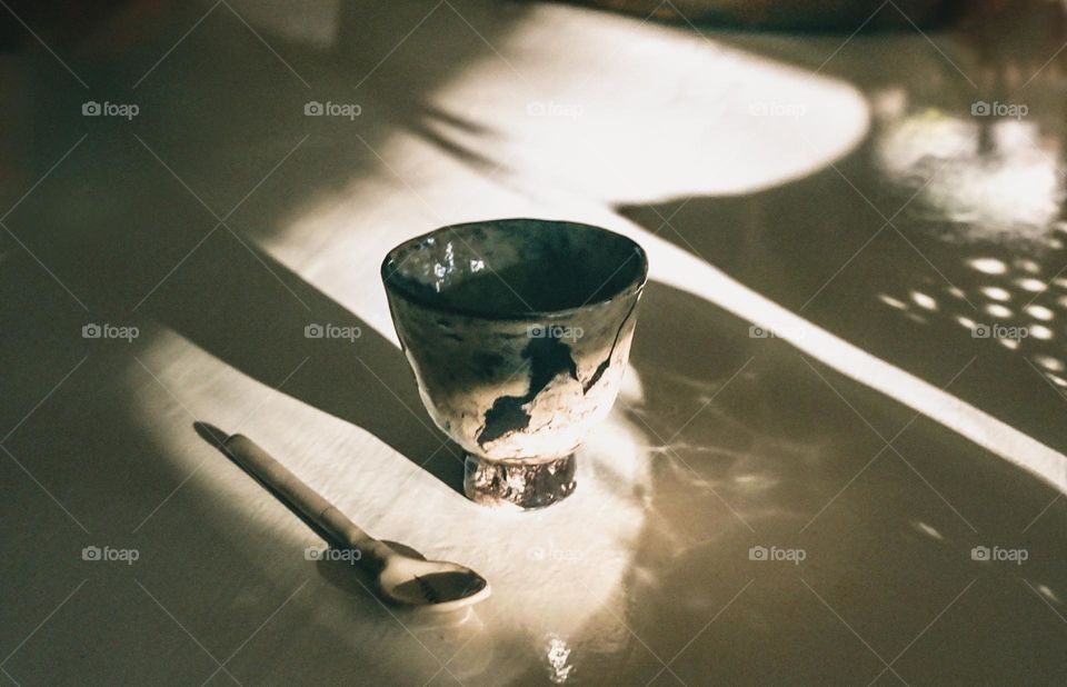Ceramic coffee cup and spoon on a table with shadowplay