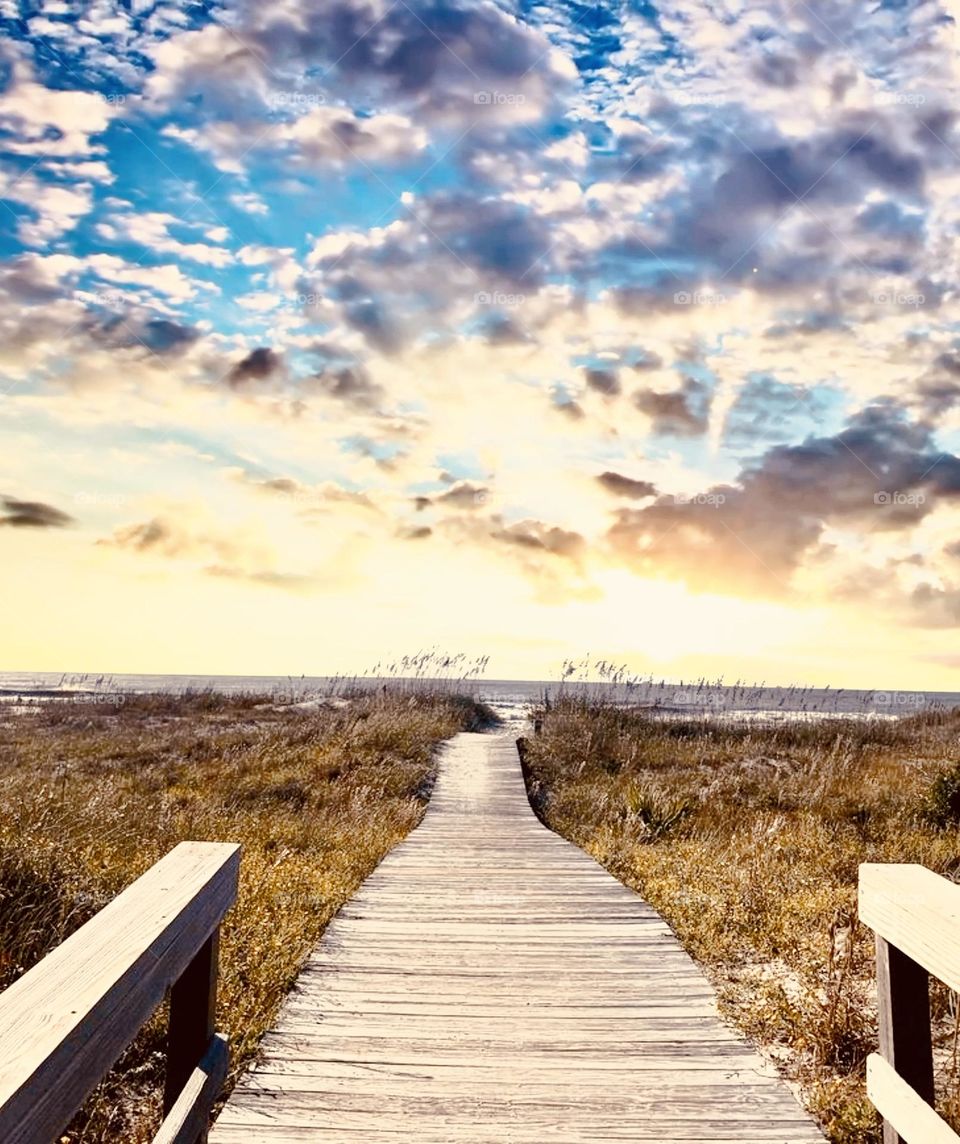 The never ending boardwalk leading an open path to the sun lit sky 