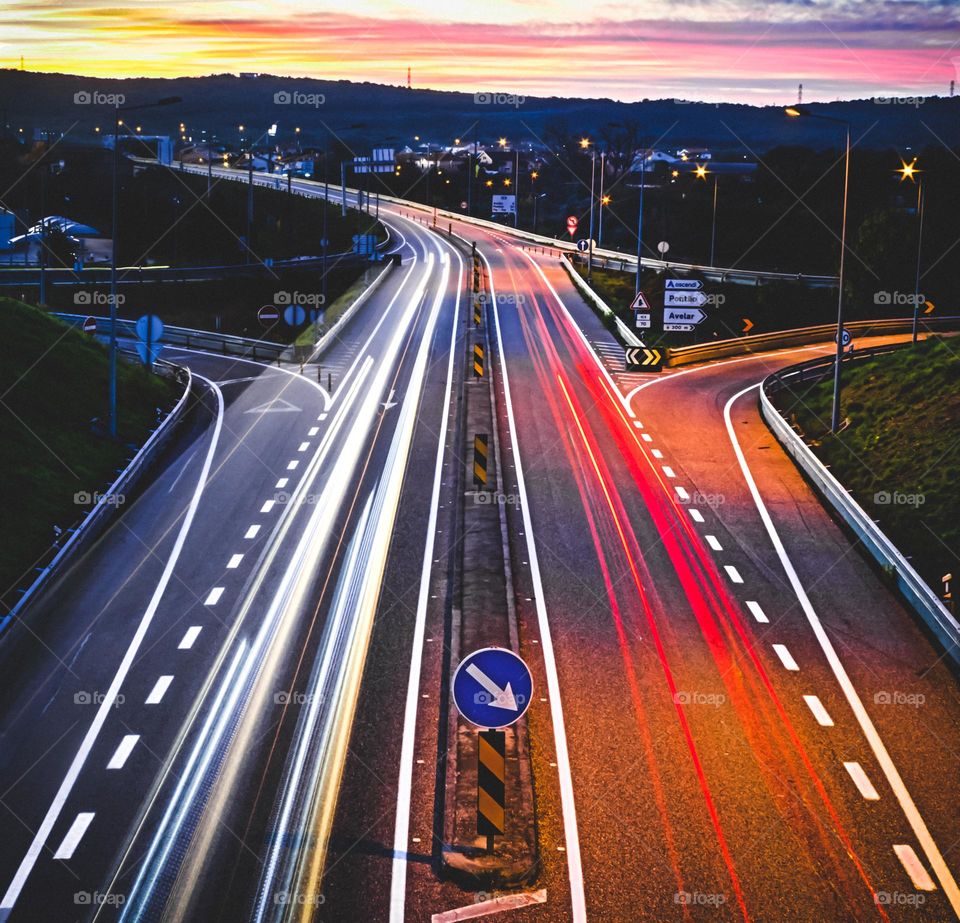 Light trails of cars on a busy stretch on road in early evening 