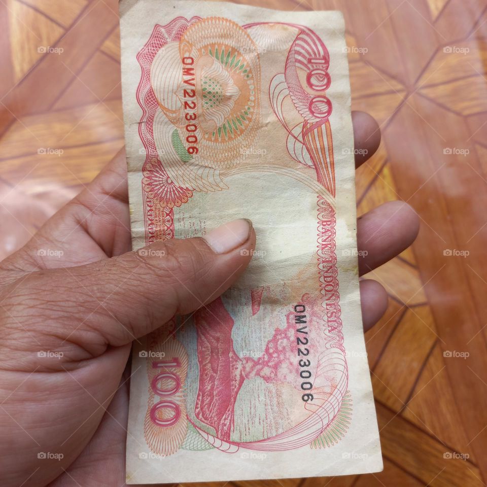 Old one hundred rupiah banknotes in hand