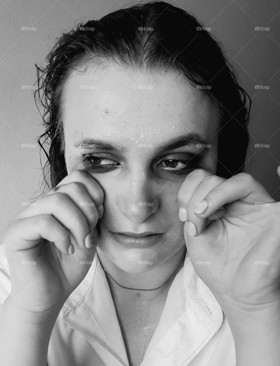 original black and white portrait of a woman wiping away tears with blurred makeup, a photo that causes sadness