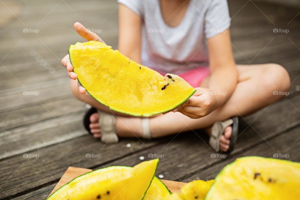 Little girl holding sliced Yellow watermelon 