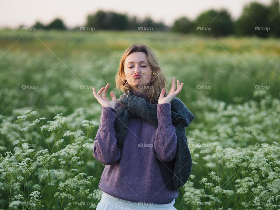 Young beautiful blonde woman in blooming field in summer day, portrait of woman 