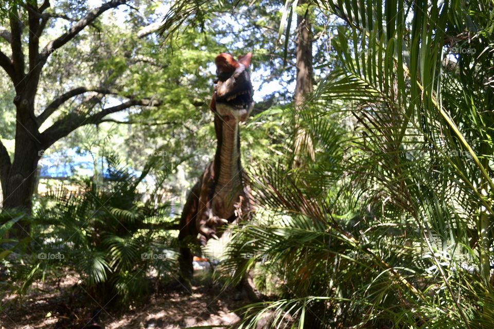 A dinosaur standing up amongst the trees.