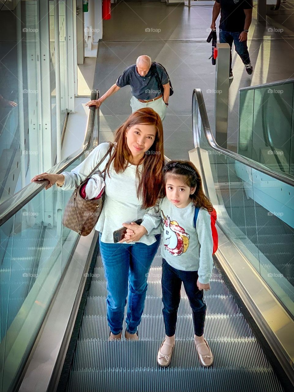 Early morning flight, mother and daughter transiting through an airport.