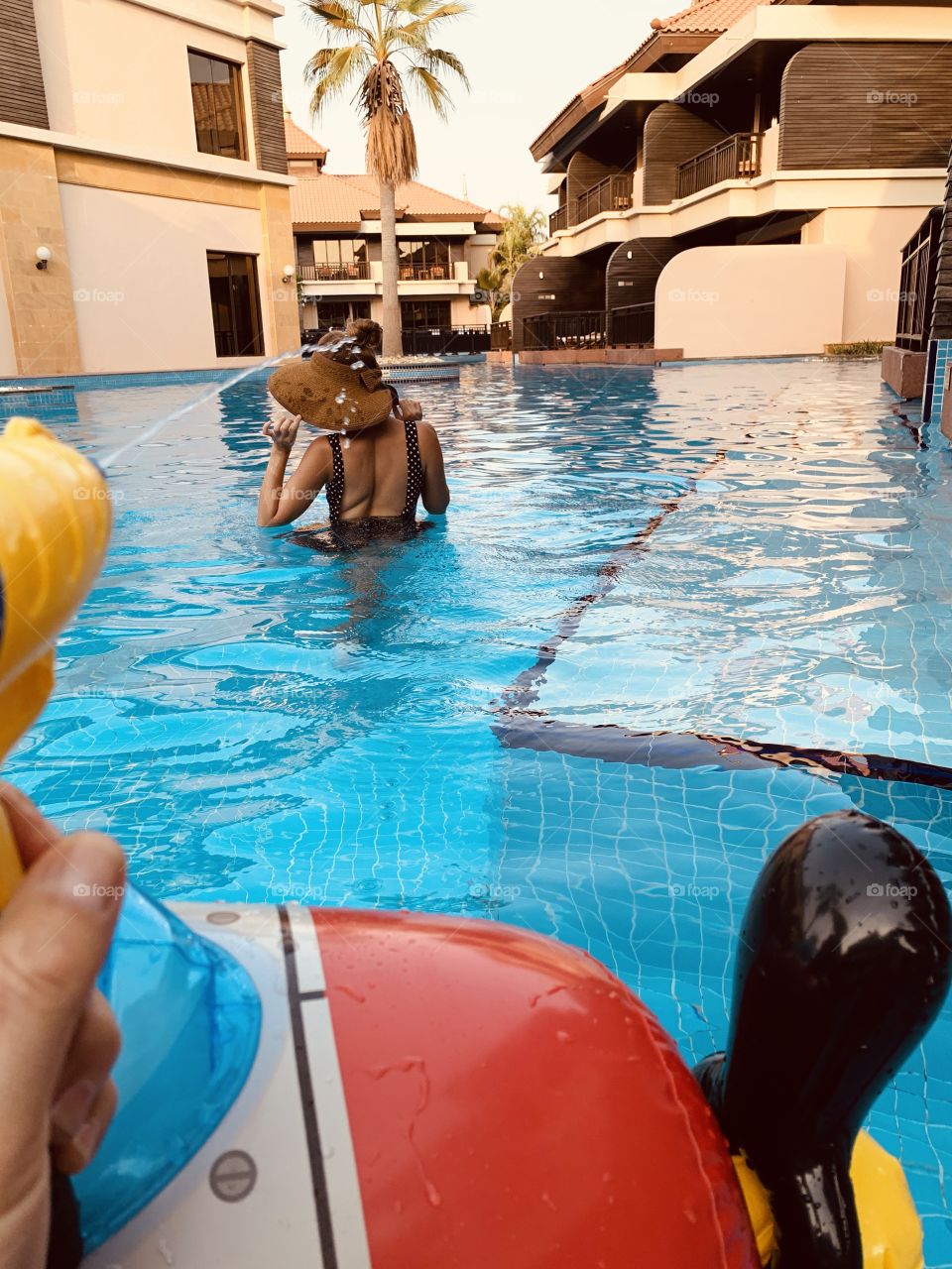 Family play in pool with water gun 