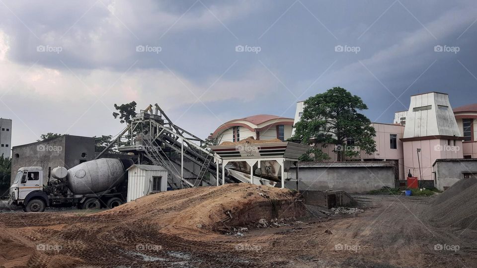 Batching Plant area with sand and stones stock. the background of plant is high rise tower.