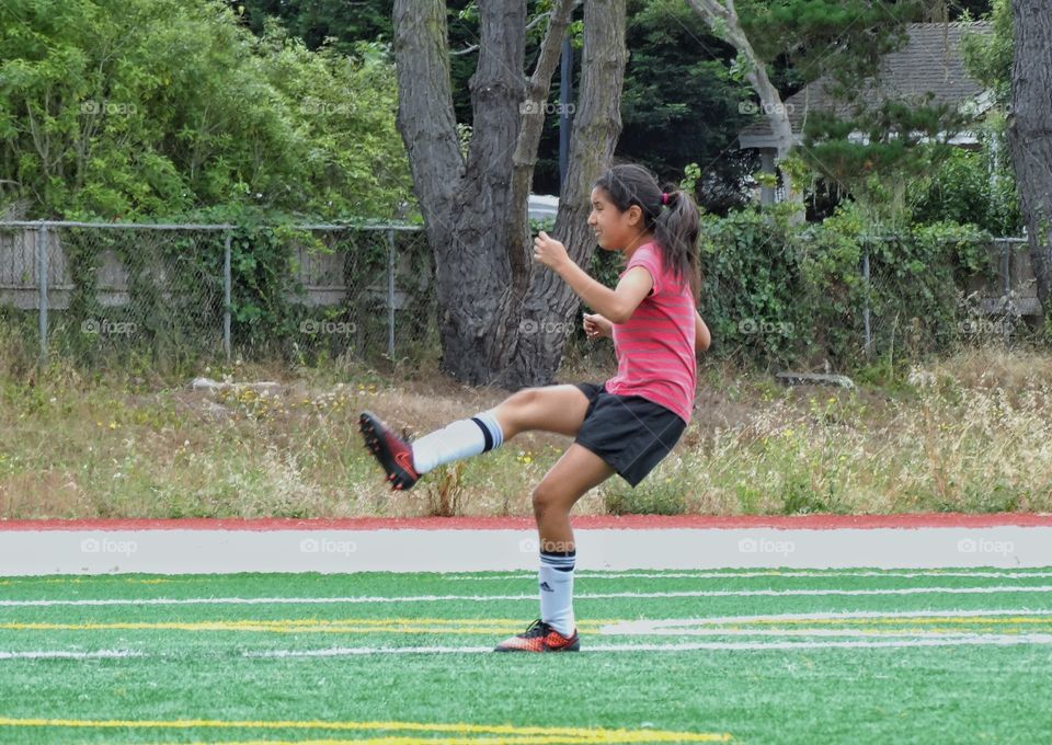 Girl Playing Soccer. Young Girl Kicking Soccer Ball For A Goal
