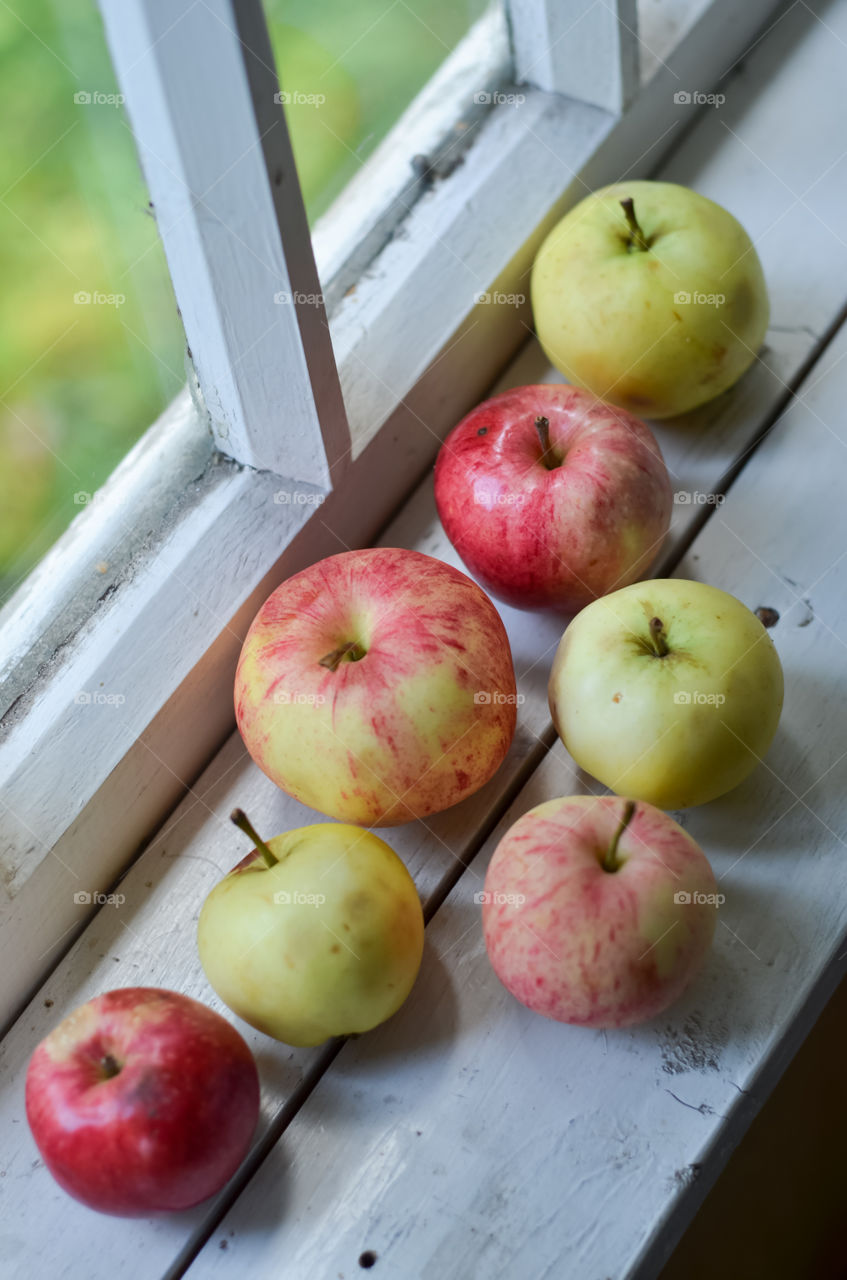 Apples on the white wooden windowsill.