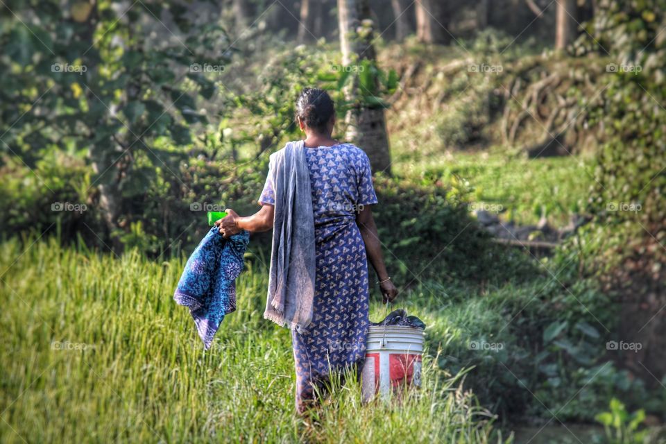 Woman walking towards the pond to wash clothes.