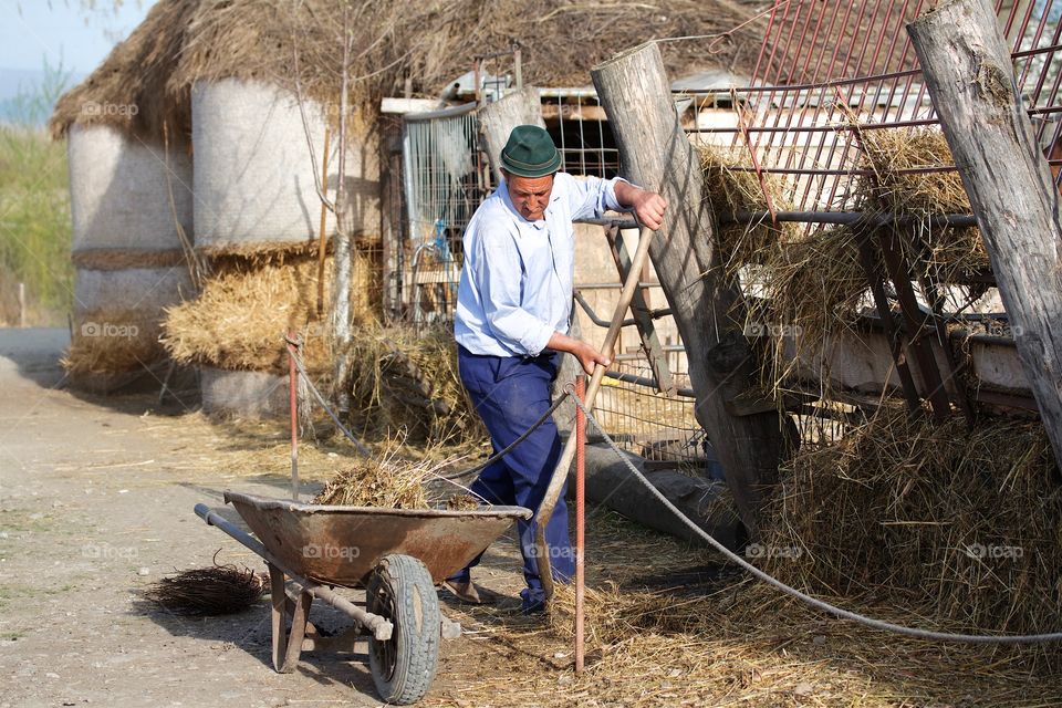 Worker loading dirt into a wheelbarrow with a shovel