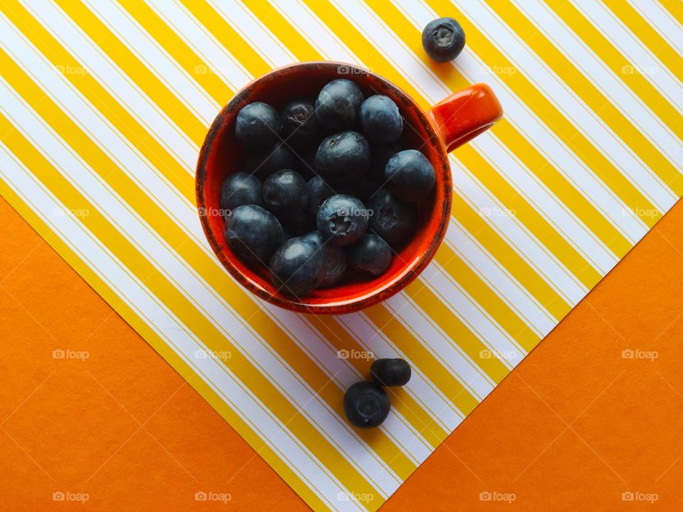 Cup of blueberries on yellow stripes