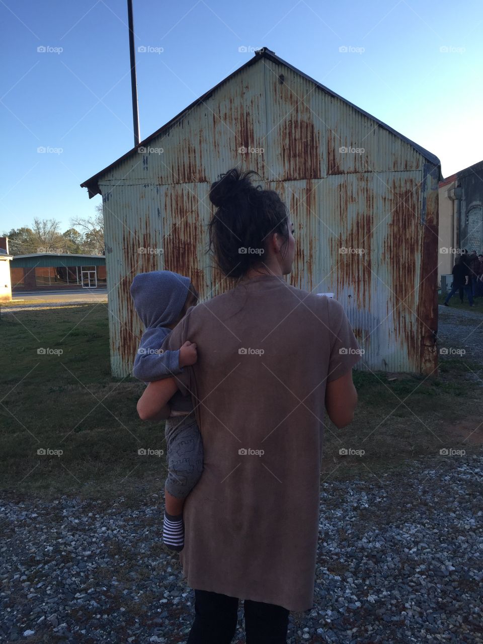Mother and one year old, against old rusty building background. 