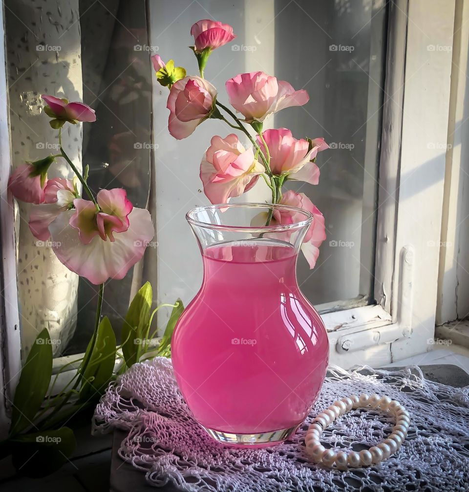 Glass vase with pink flowers in the pink water