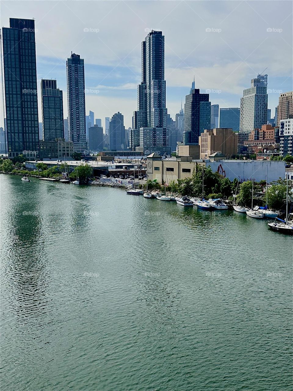 This is „Newtown Creek“ seen from the „Pulaski Bridge“ that connects LIC, Queens to „Greenpoint“, Brooklyn. Across the water of the „East River“ in the distance we see „Manhattan“. 2024. Hypnotic Productions