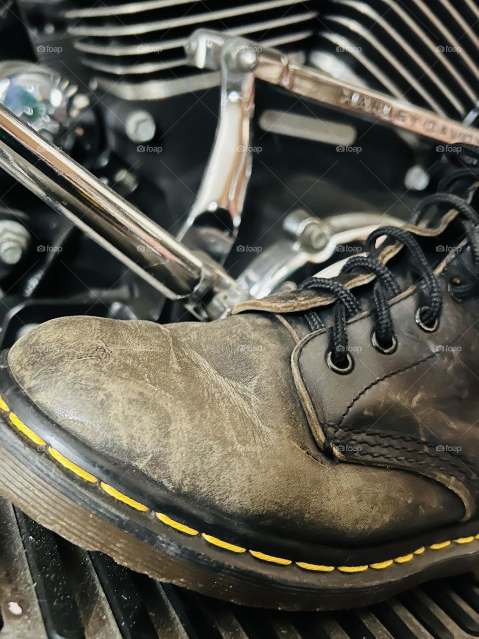 Closeup of worn, older Doc Marten classic boots with motorcycle in background 