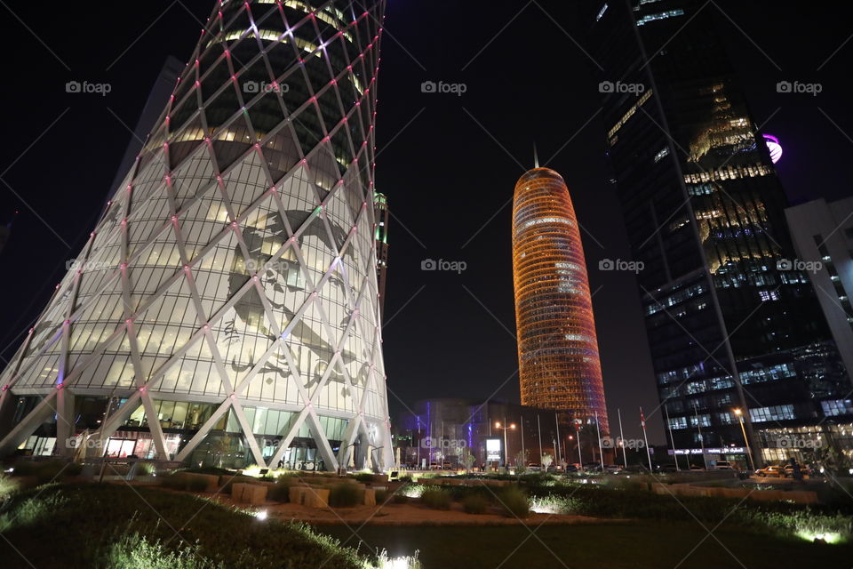 An image of Qatari emir Sheikh Tamim bin Hamad al Thani on the side of the Tornado Tower in Doha, Qatar, with the Doha Tower lit up in the background.