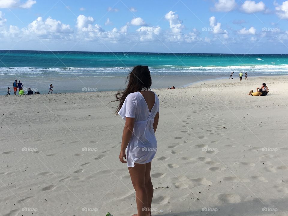 Girl in white dress gazing out to the Cuban sea 