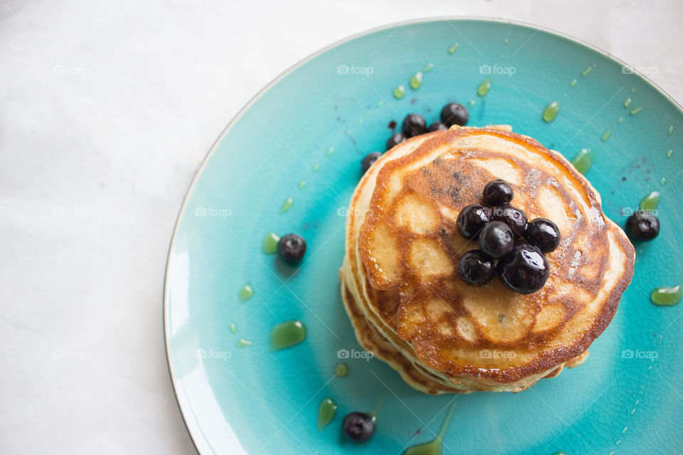 Stack of blueberry pancakes. Stack of blueberry pancakes and syrup on a blue plate. Overhead shot. 