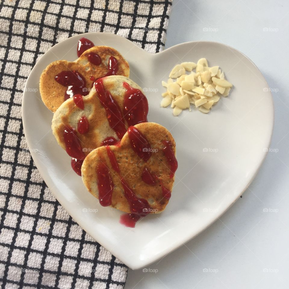 Heart shaped protein pancakes on heart shaped plate with almonds and jam