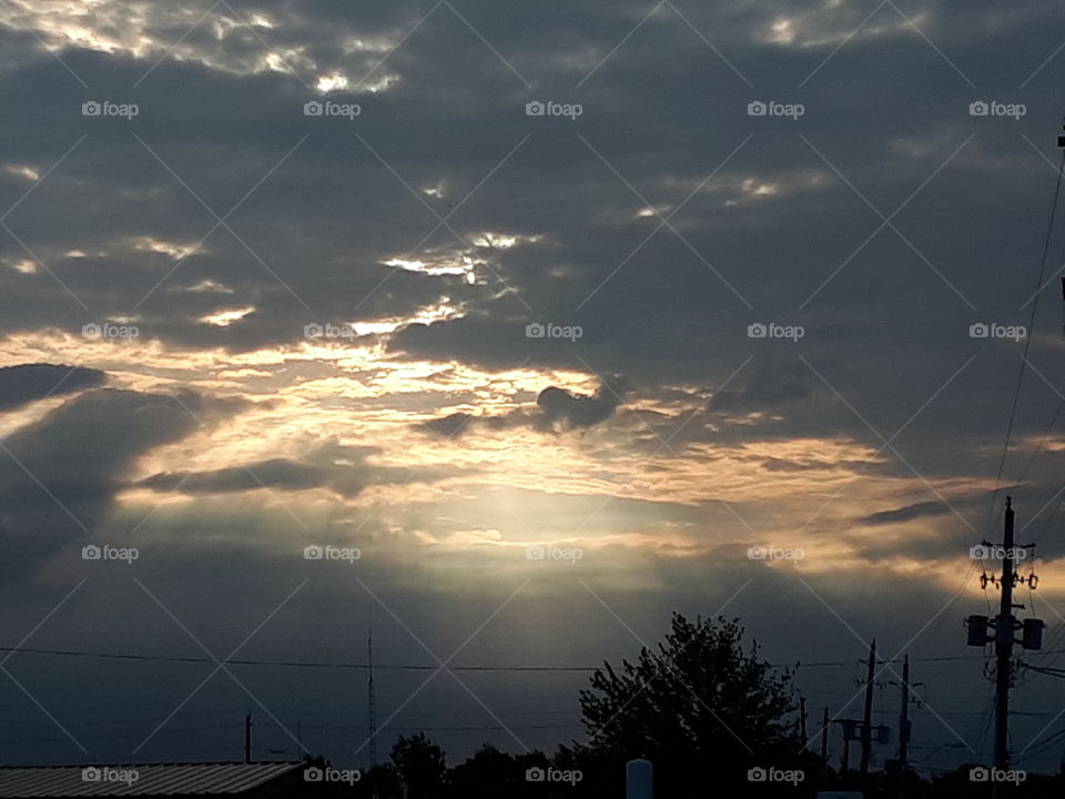 Sunrays cutting through a cloudy grey sky.