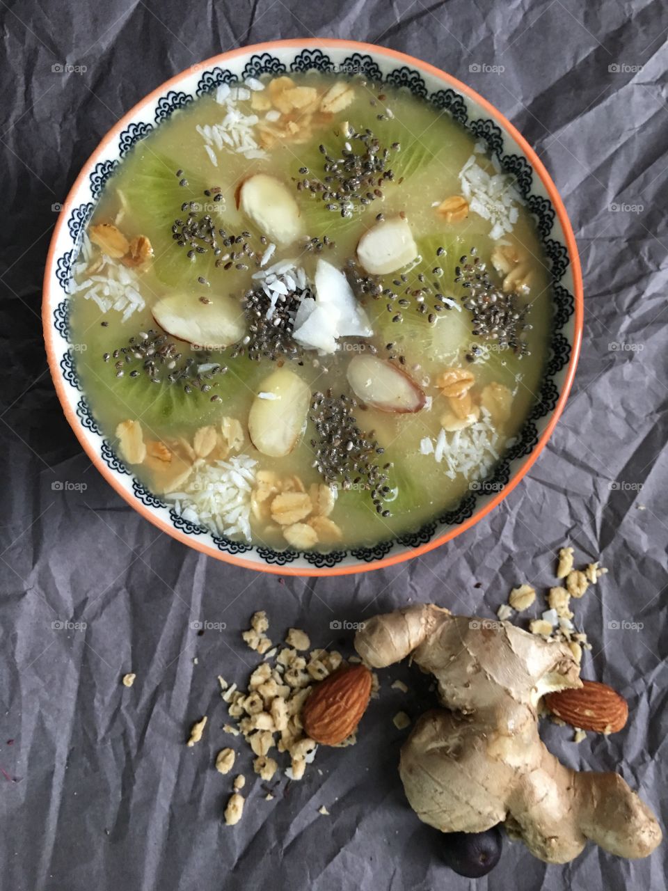 Green fruit smoothie bowl with almond, chia seed, ginger root, oatmeal, kiwi and coconut elevated view healthy lifestyle and eating choices food photography background 