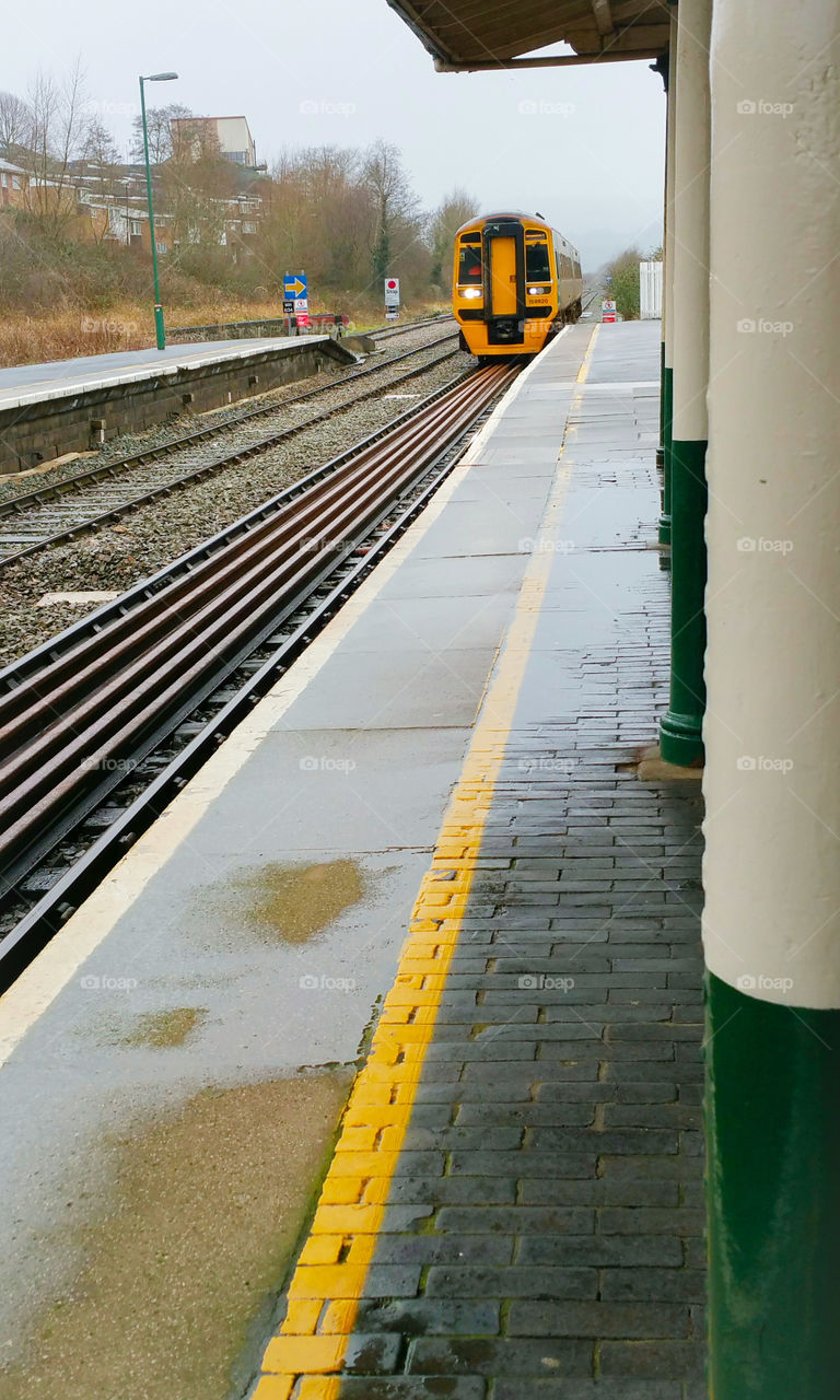 A yellow train arriving at a station