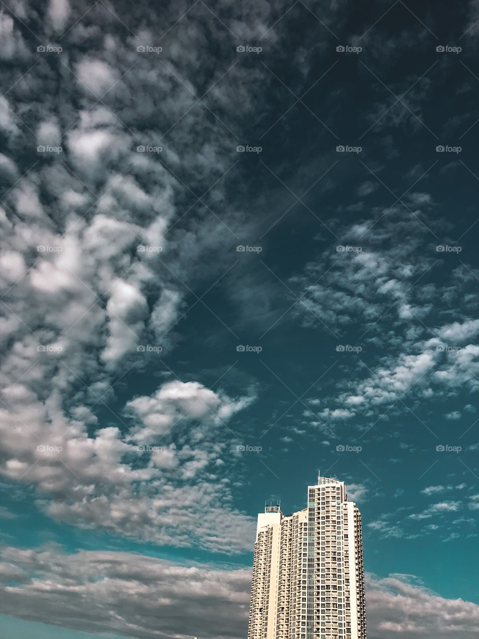 Capturing the upper part of the apartment building with a clear blue sky and clouds.