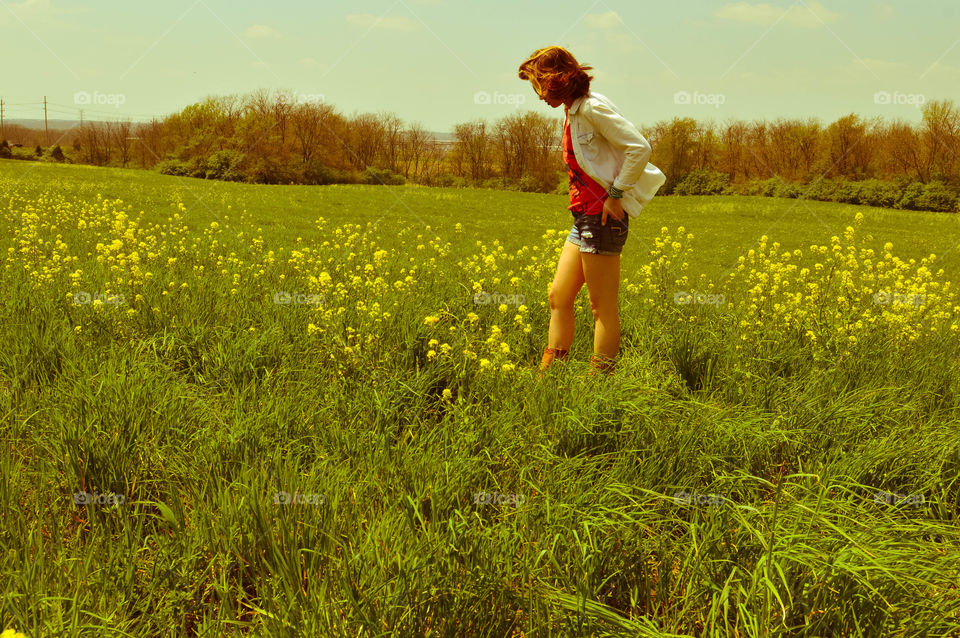 Woman standing in a field of flowers on a windy summer day