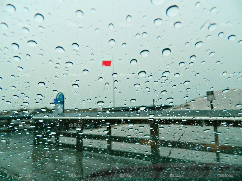 Liquids are cool - A rain doted windshield displays a red warning flag warning swimmers that the Gulf of Mexico is dangerous 