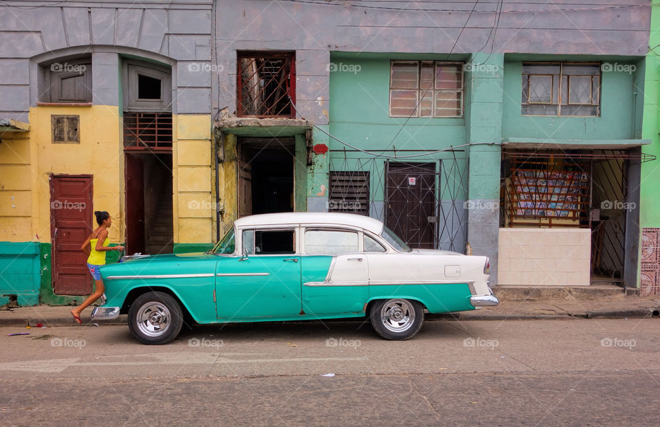 Havana, Cuba - December 19, 2013: Classic American car, unidentified girl and colourful street scene in Havana, Cuba. 