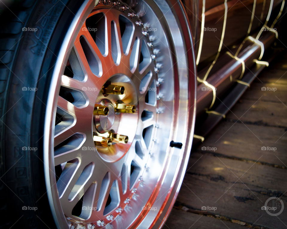 Custom three piece wheel with gold lug nuts and stretched tires on a Subaru Wrx