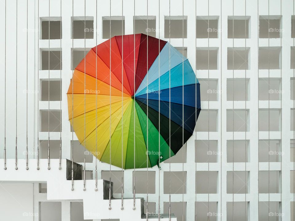 A colorful umbrella against a square perforated wall