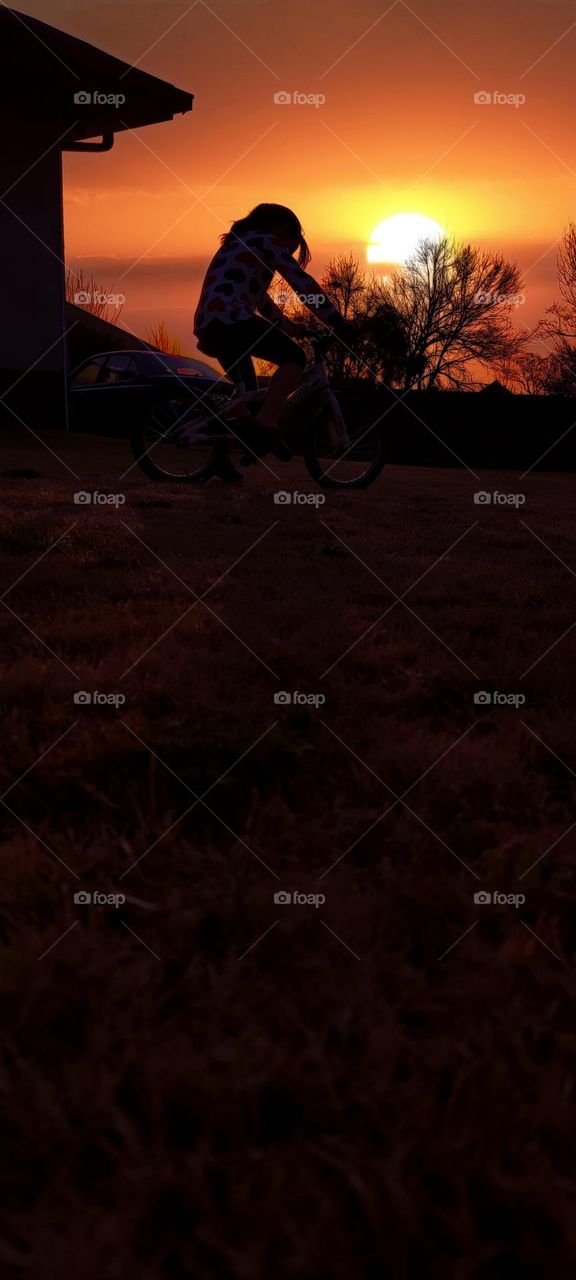 Girl on her bicycle, Sunset background