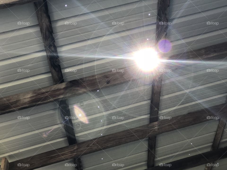 Sun peeking through hole in barn roof