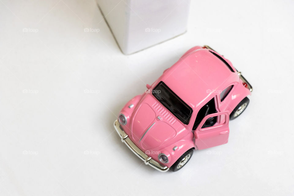 Flat lay - little pink car under a  table