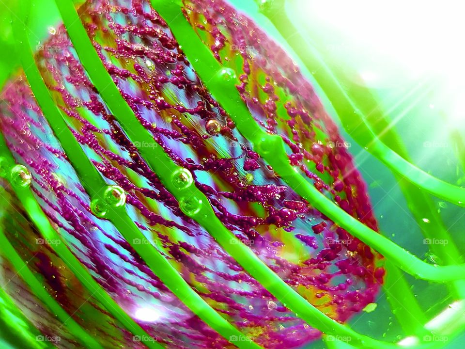 Abstract - close up of light Illuminated glass art with lime green and raspberry pink lines, shapes, textures, and patterns.