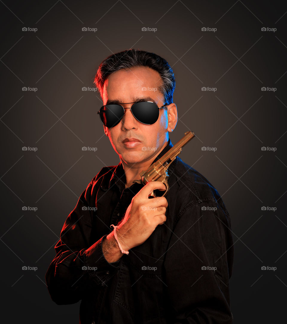 Indian man with a gun wearing sunglasses mafia gangster look