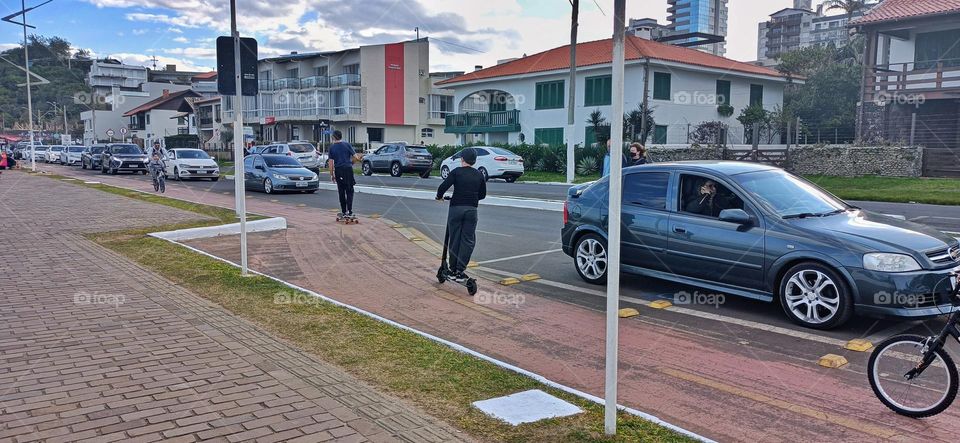 Man skateboarding boy on scooter
