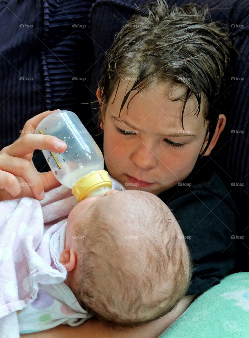 Young Boy Feeding His Baby Sister A Bottle
