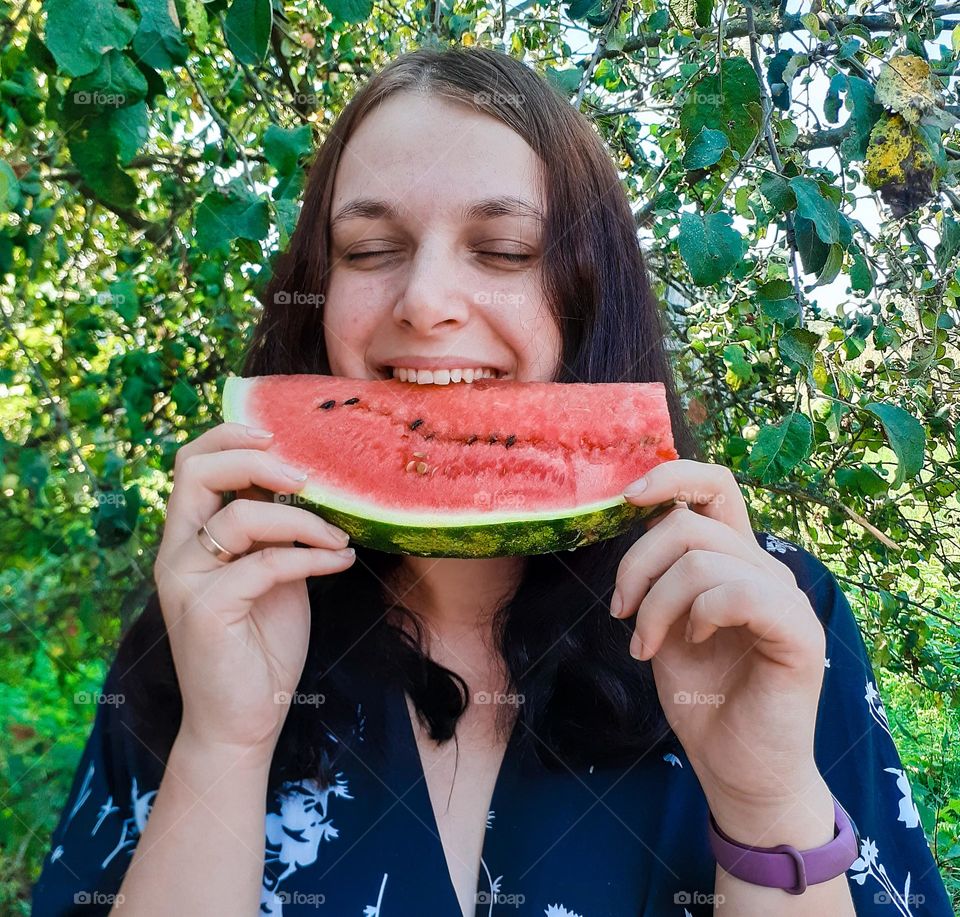 The girl enjoys a large piece of fresh watermelon