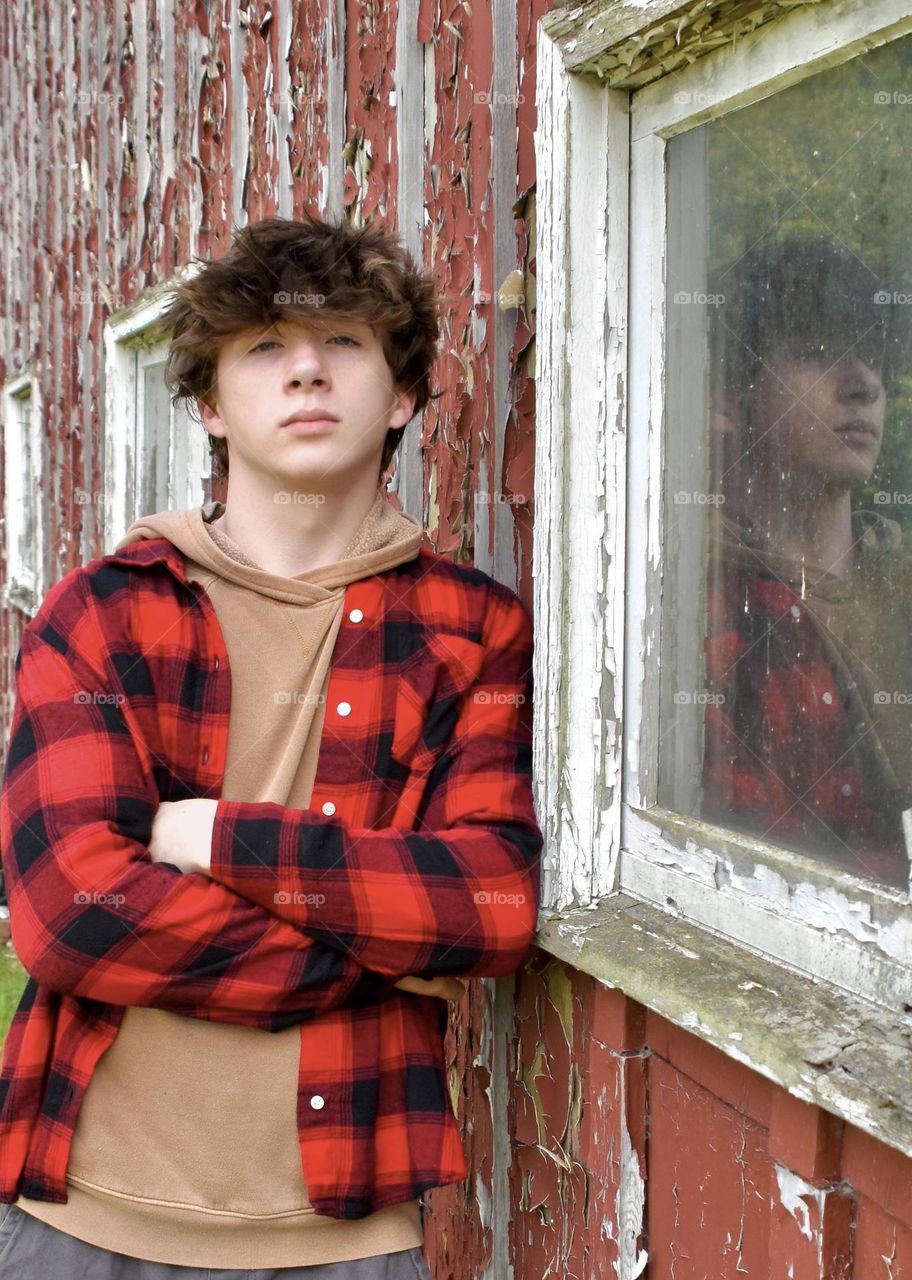 Young man leaning against a barn