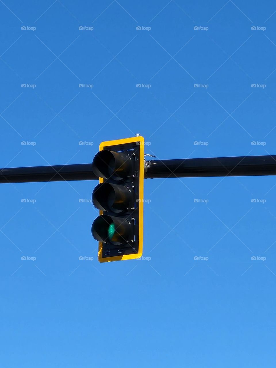 suspended green traffic light against blue sky