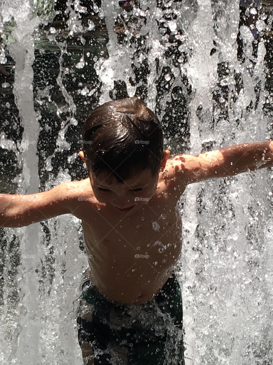 Little boy playing in a splash pad.