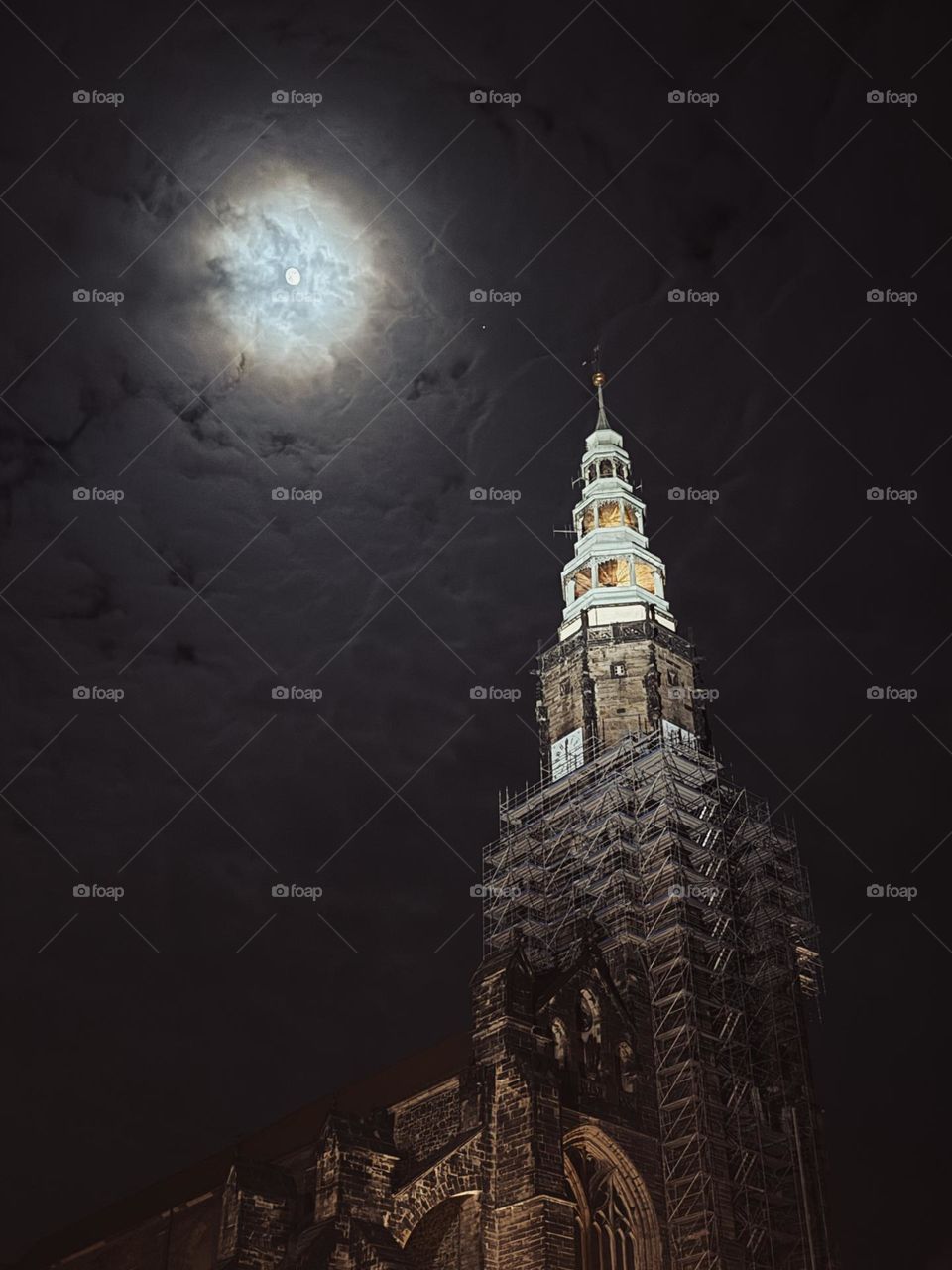 Old gothic cathedral during the renovation, dark night sky with a full moon in the background. Dark colors 