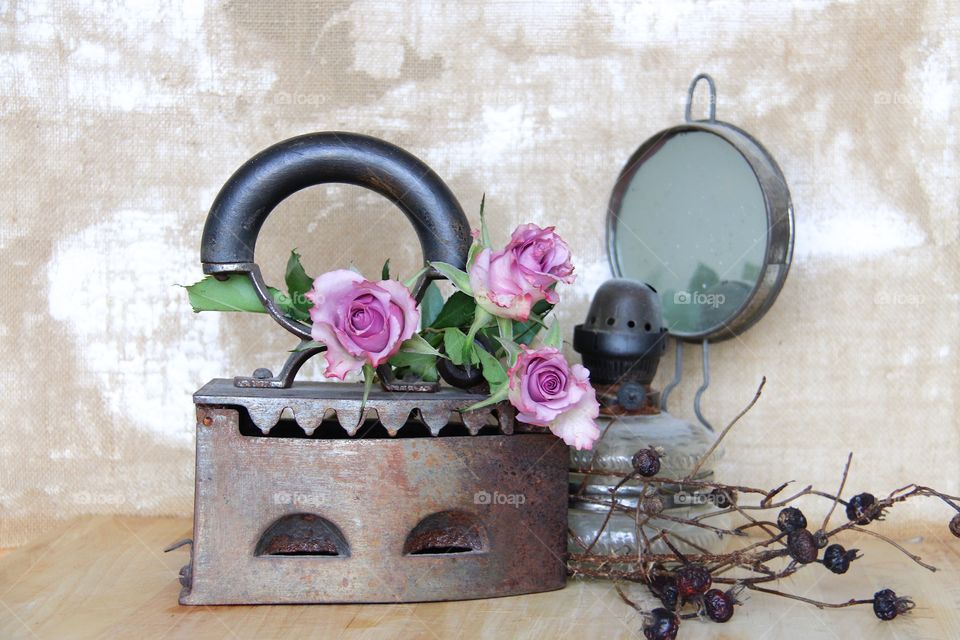 Pink roses in a iron and an old oil lamp