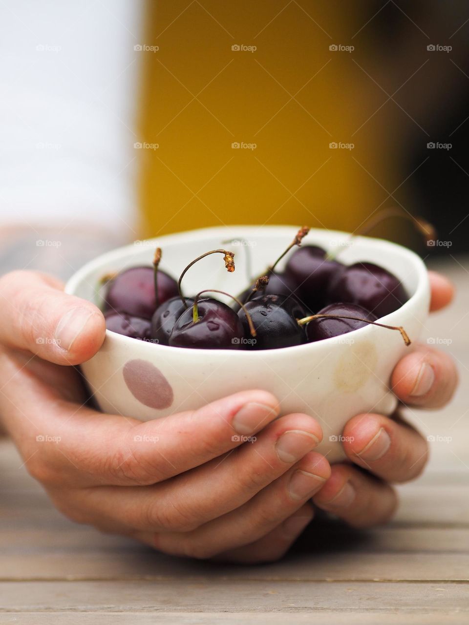 Unknown woman holding a ceramic plate with fresh cherries, closeup photo