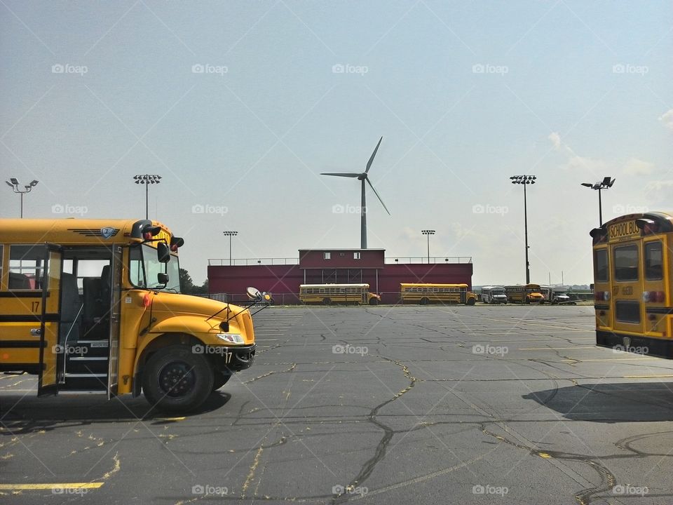 school wind power. a school bus in front of a wind terbine
