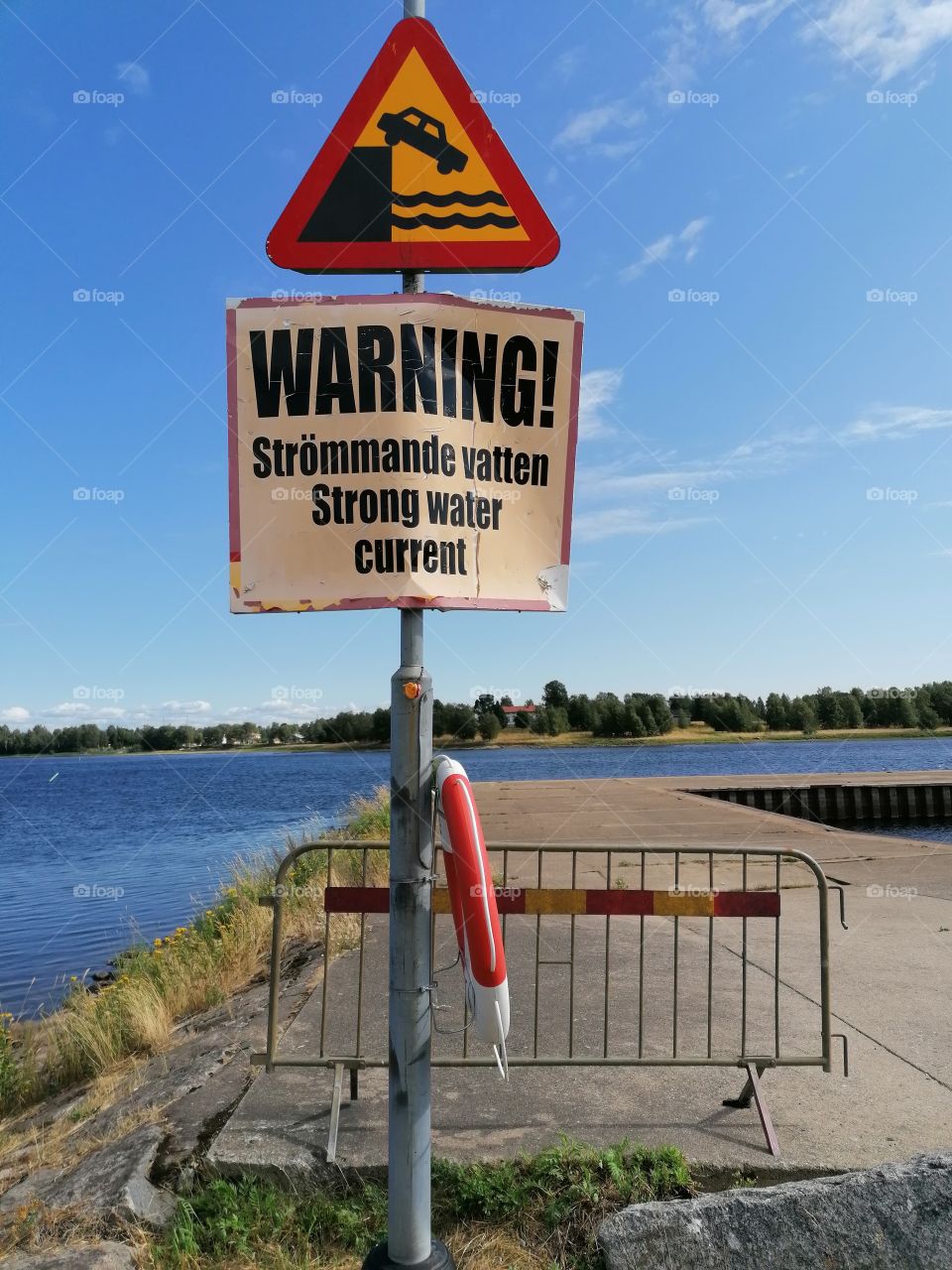 A warning sign at the end of the road that the car will drop into the river if you drive there.