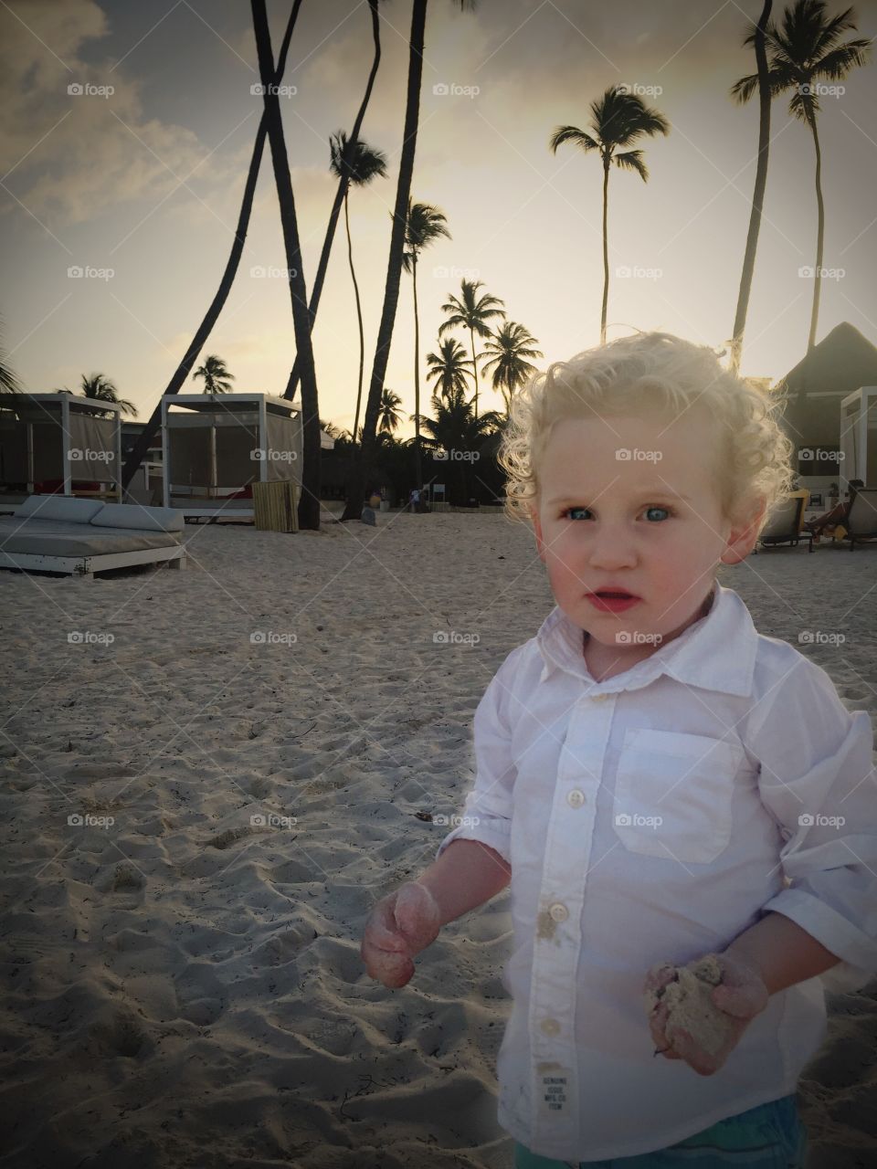 Toddler boy on beach holding sand